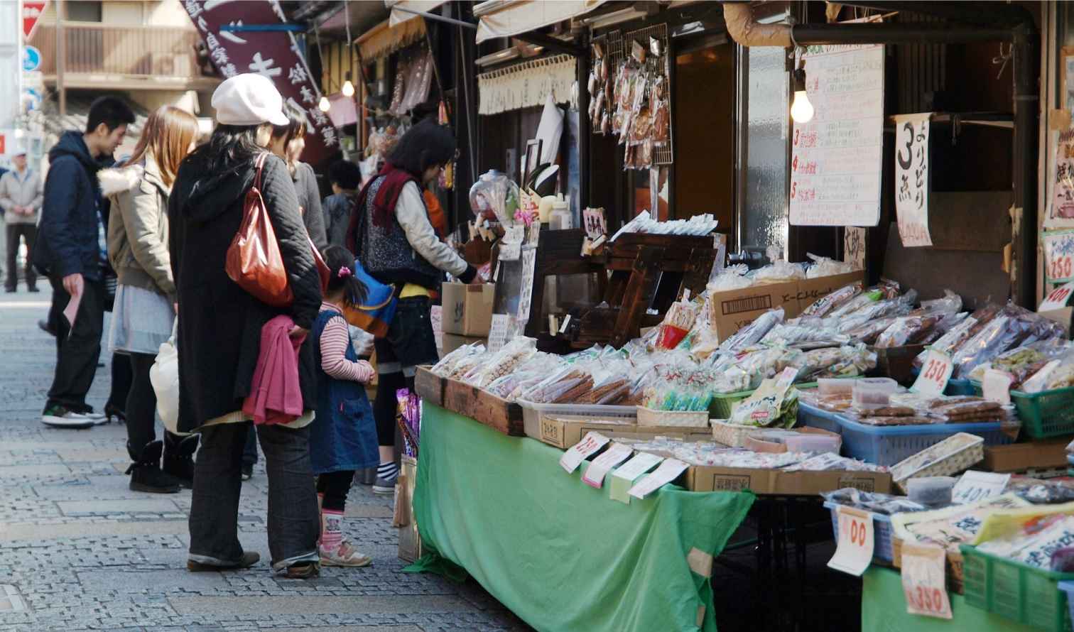 Outdoor market in Japan with people browsing various food stalls in Kawagoe