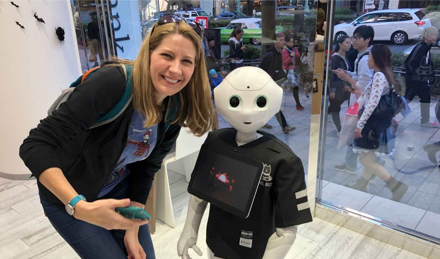 A woman poses with a humanoid robot inside a tech store  in Tokyo
