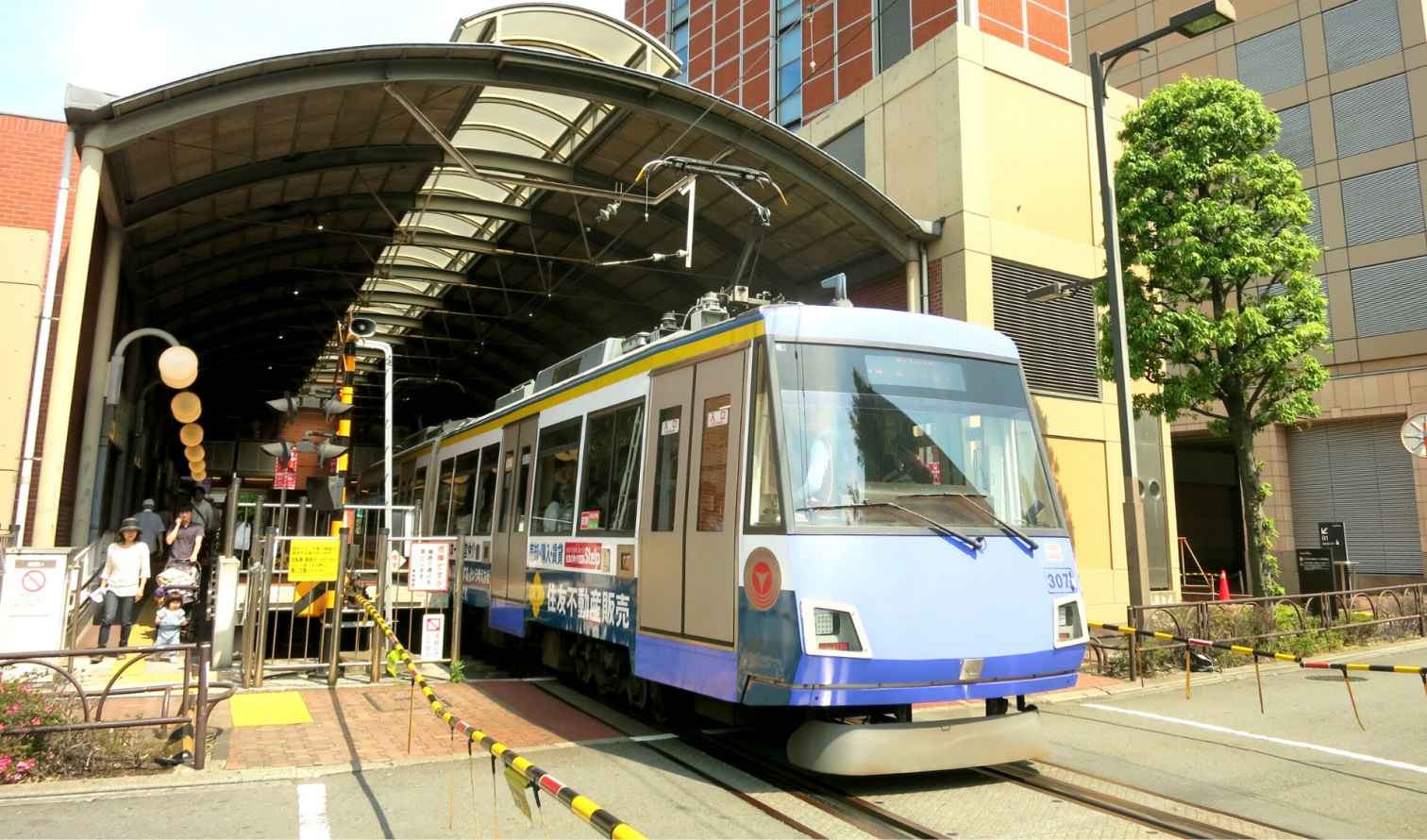 Electric tram at Orix Theater, Osaka, near entrance with pedestrians nearby.