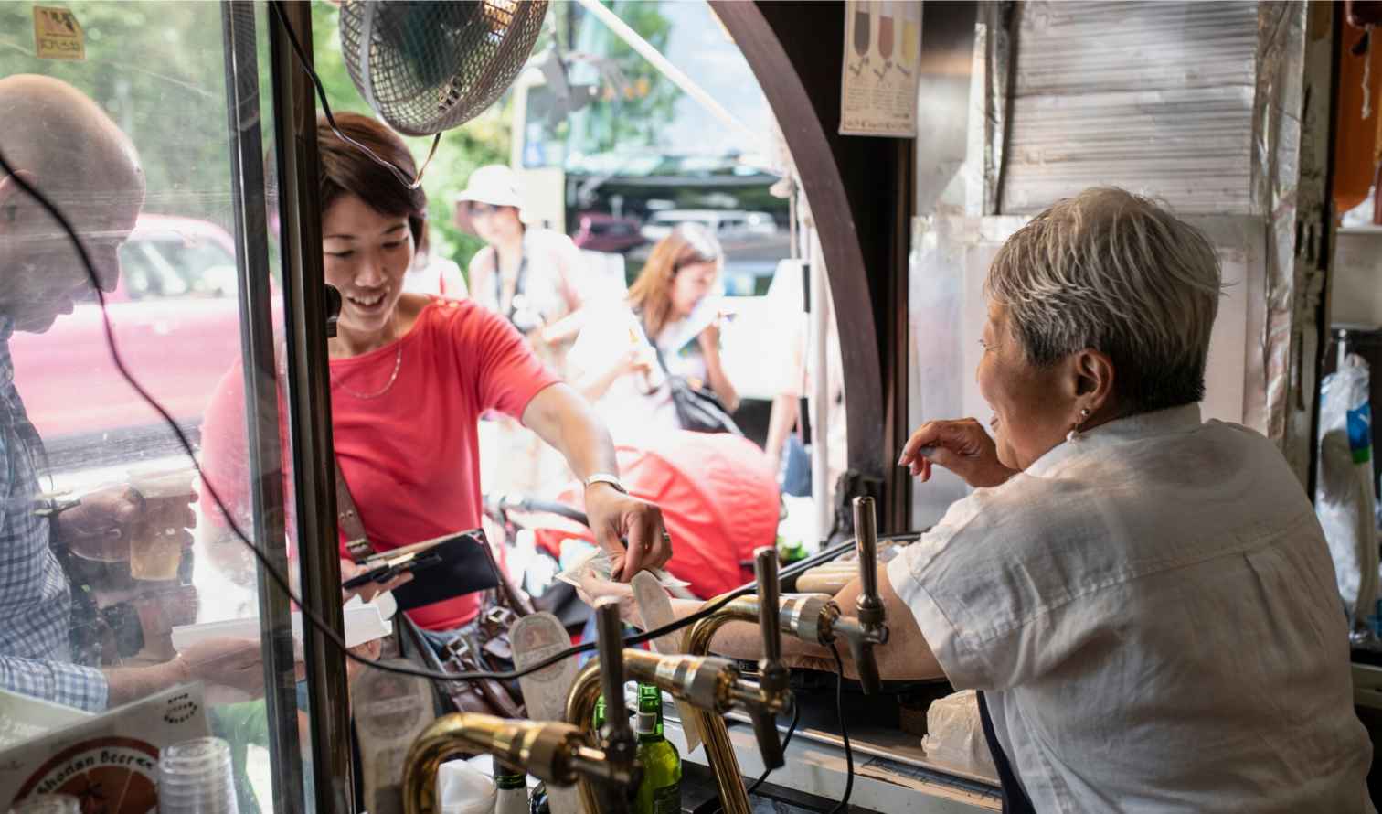 People interacting at a street food stall in Kamakura, in Japan.