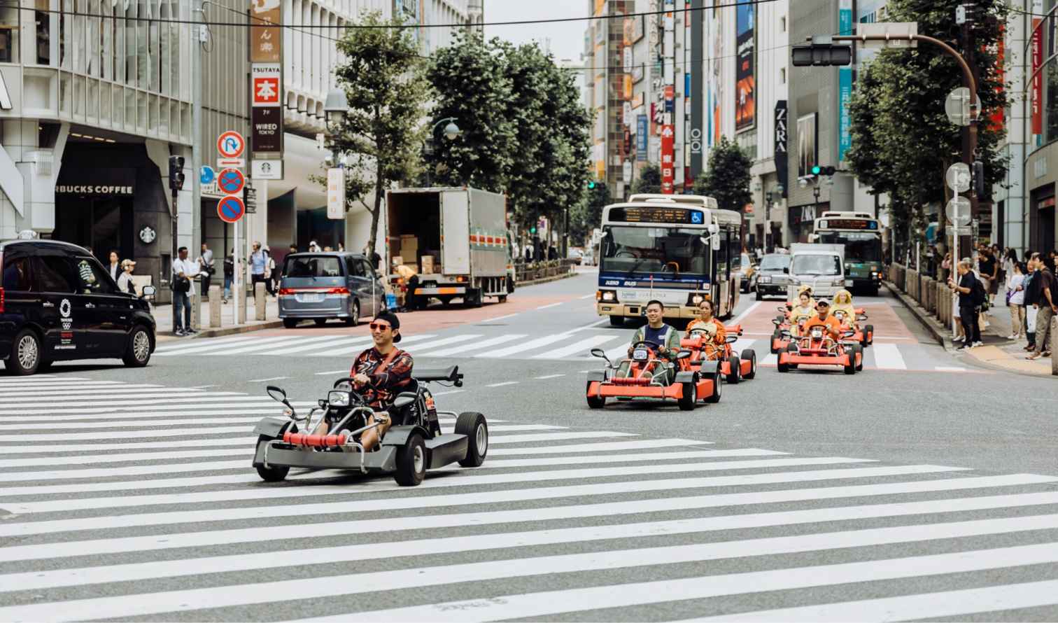 Go-kart riders crossing a busy intersection in Shibuya, Tokyo.