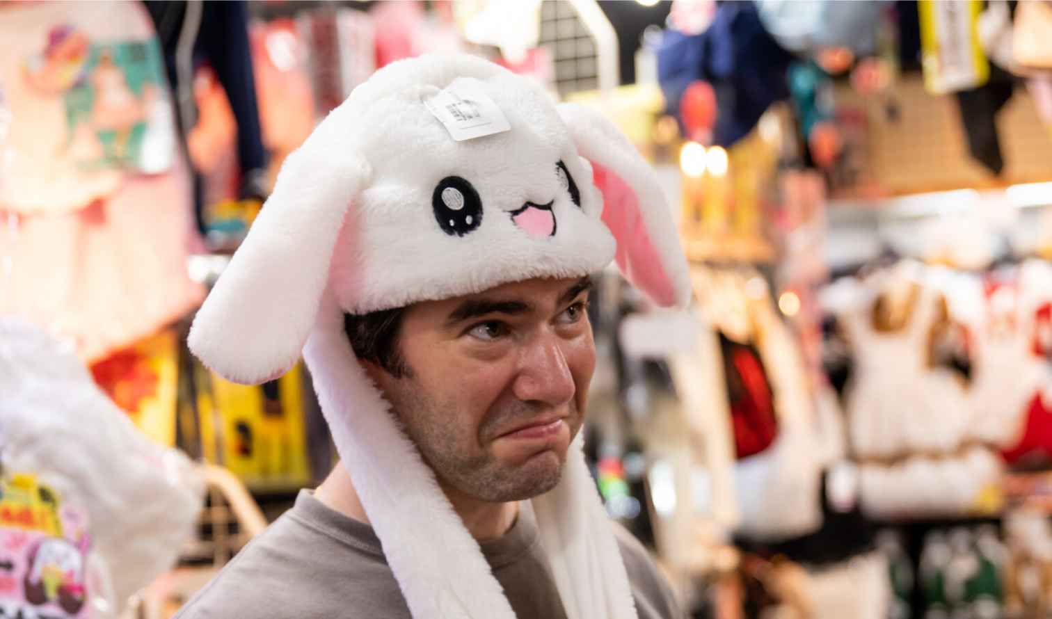 Person wearing a white animal-themed hat in a clothing store in Tokyo