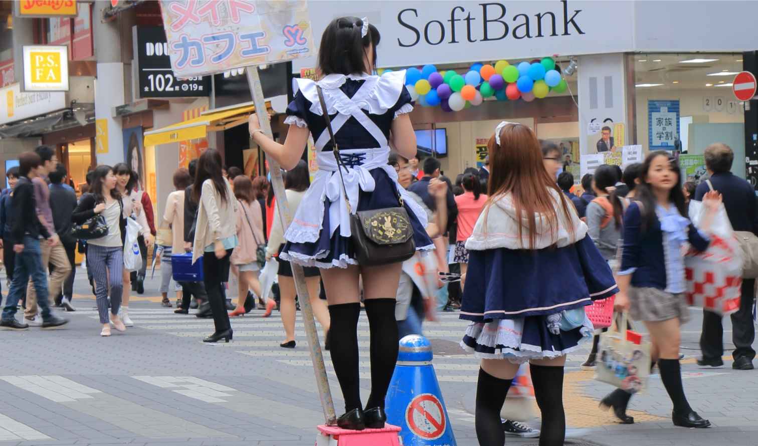 People crossing a street with maid cafe promotions in Akihabara, Tokyo.