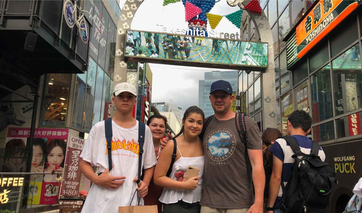 Group of people standing under Takeshita Street sign in Tokyo.