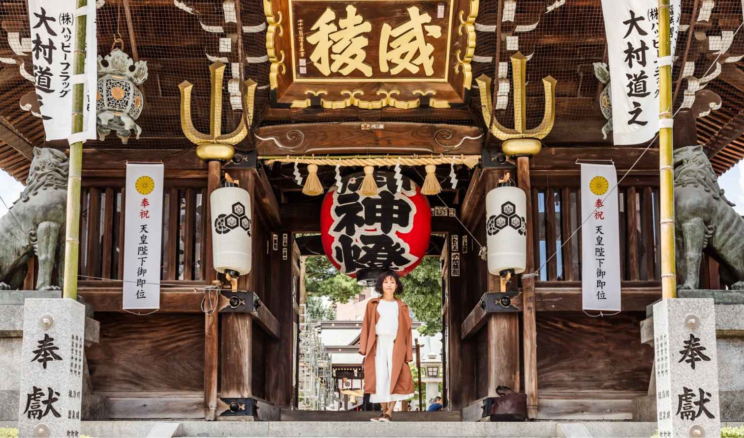 Person standing in the entrance of a traditional Japanese shrine with lanterns in Fukuoka