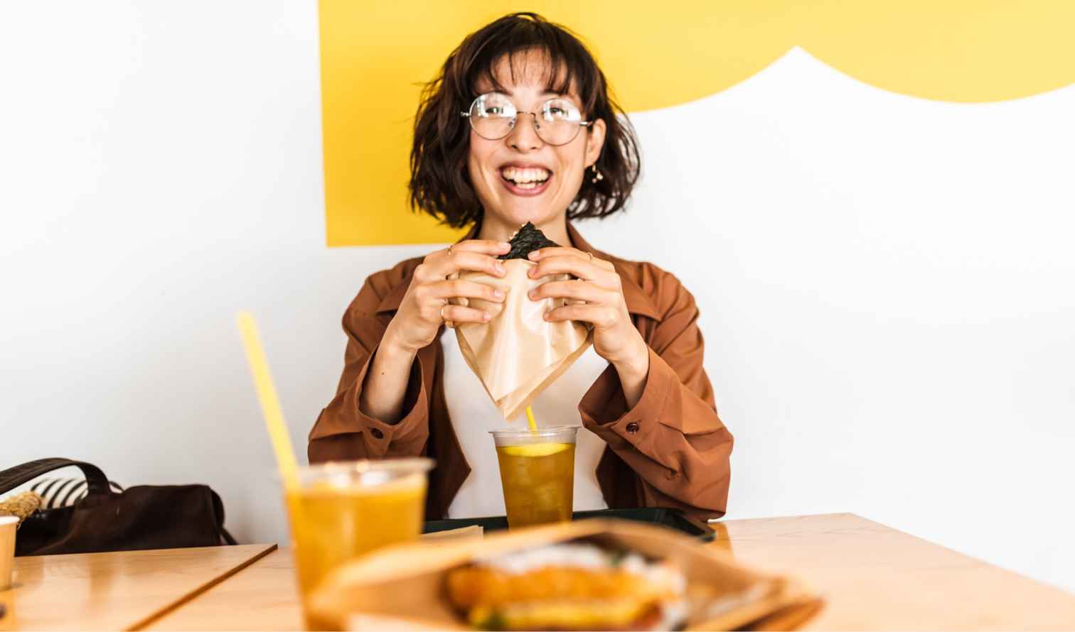 Person holding a snack in a cafe with a yellow accent wall in Fukuoka