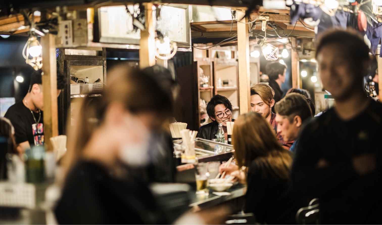 People dining at a small food stall in a market area in Fukuoka