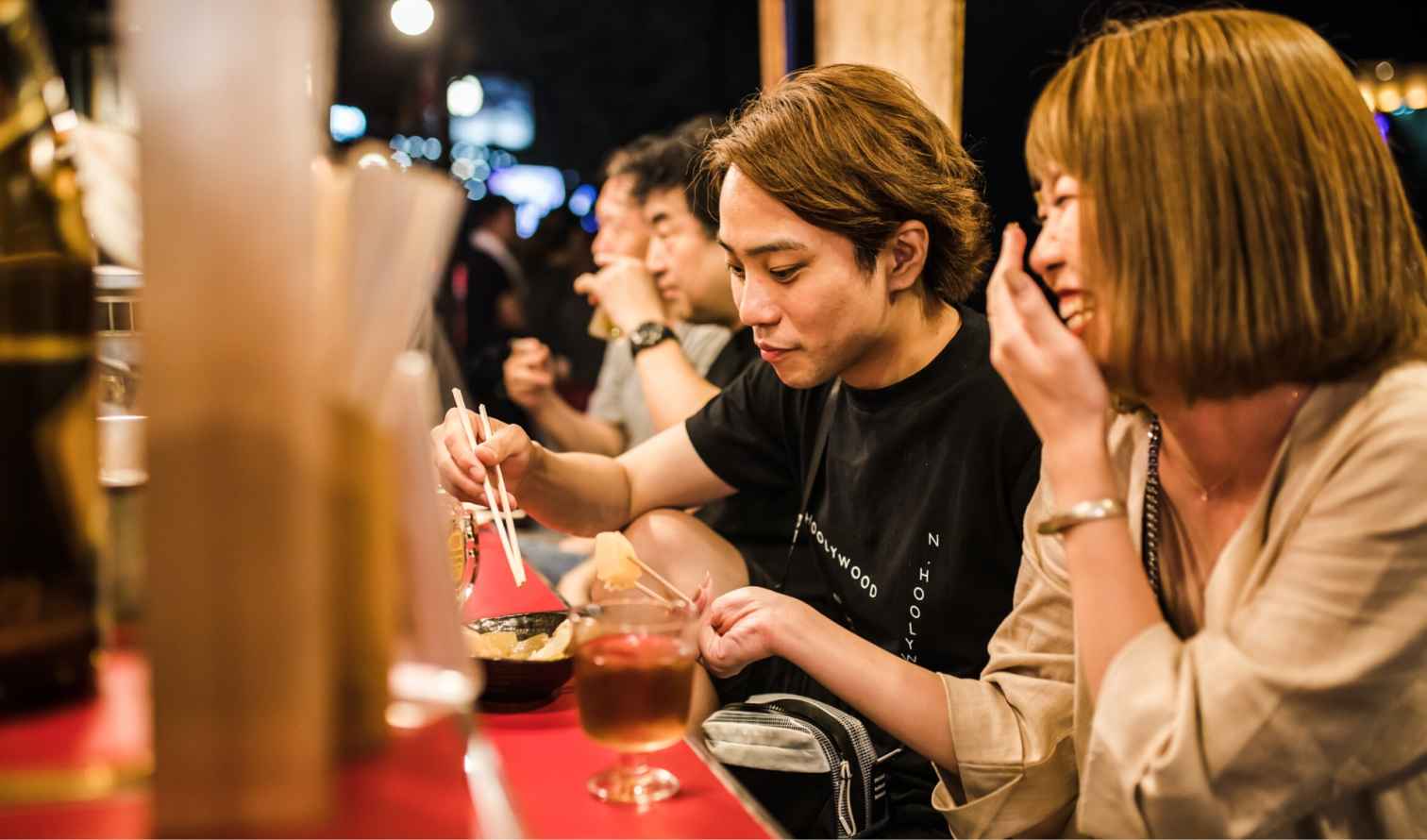 People eating at a street food stall in Japan at night in Fukuoka