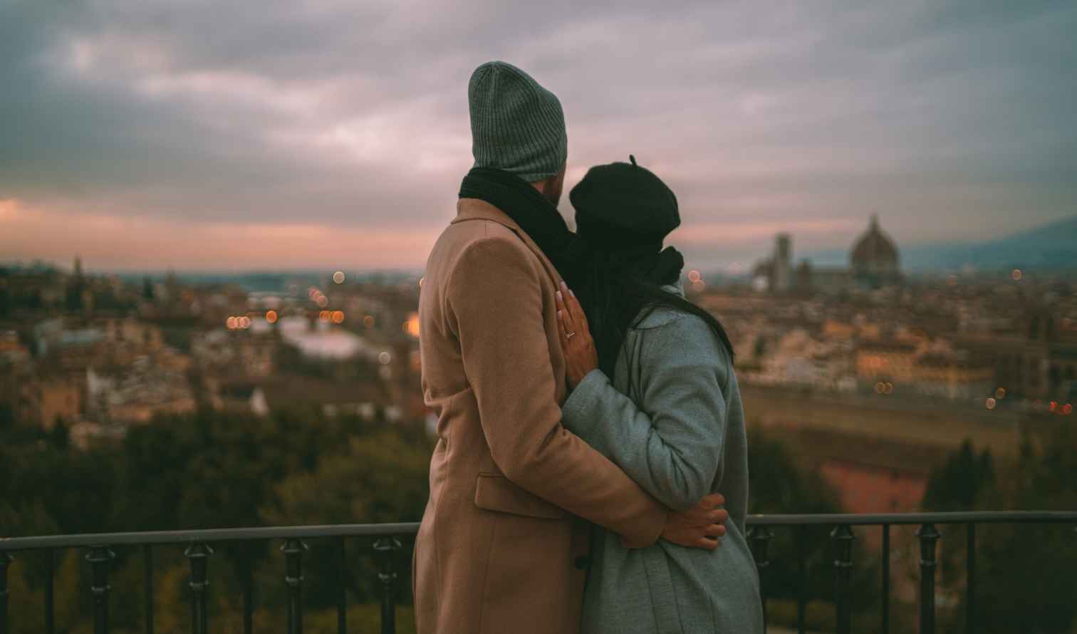 Two people in coats overlook the cityscape of Florence from a viewpoint.
