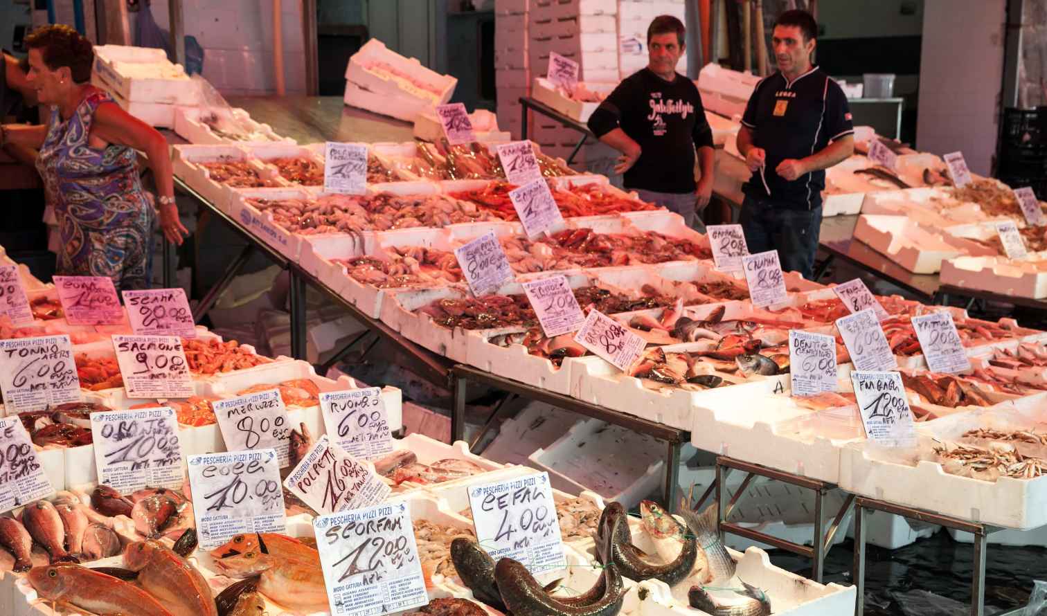 Fish market stall with various fish and seafood on display with price tag in Naples