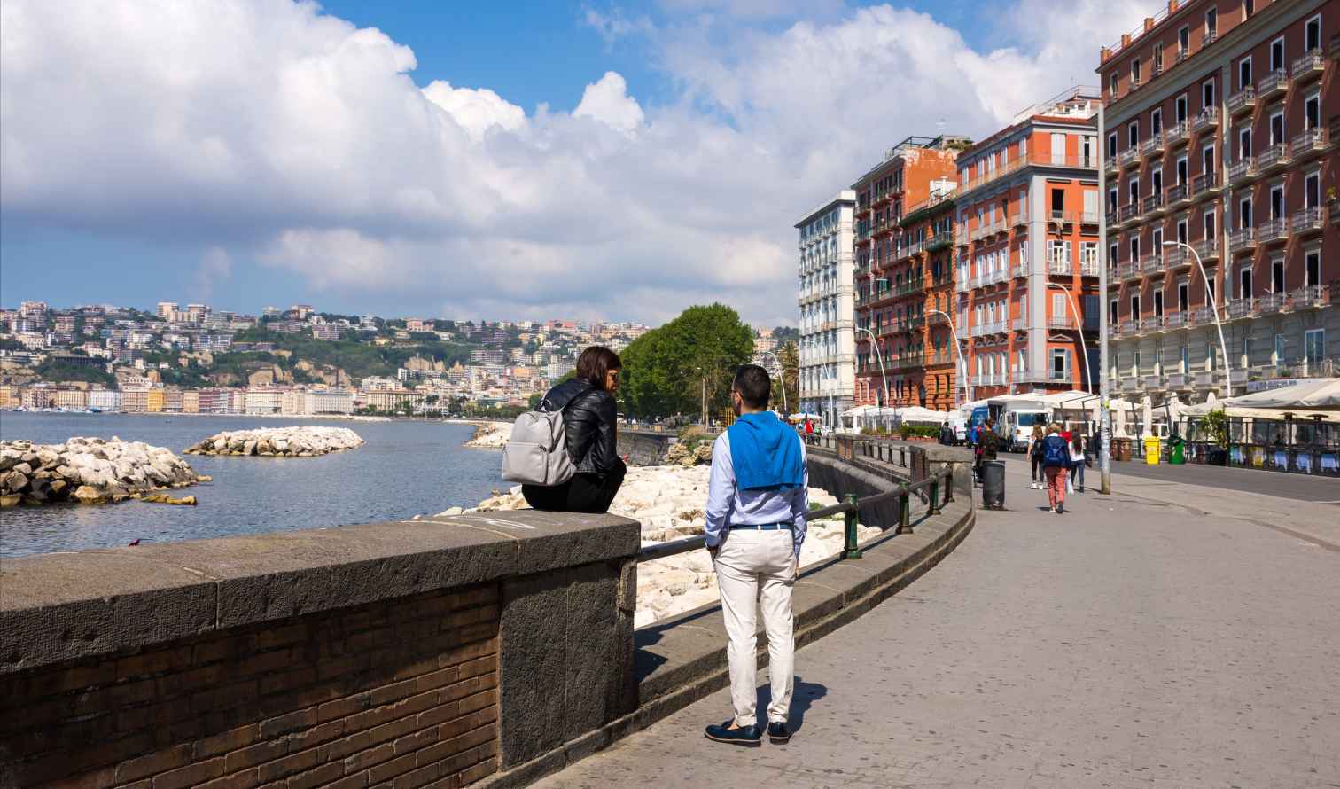 Two people converse by the waterfront in Naples, Italy.