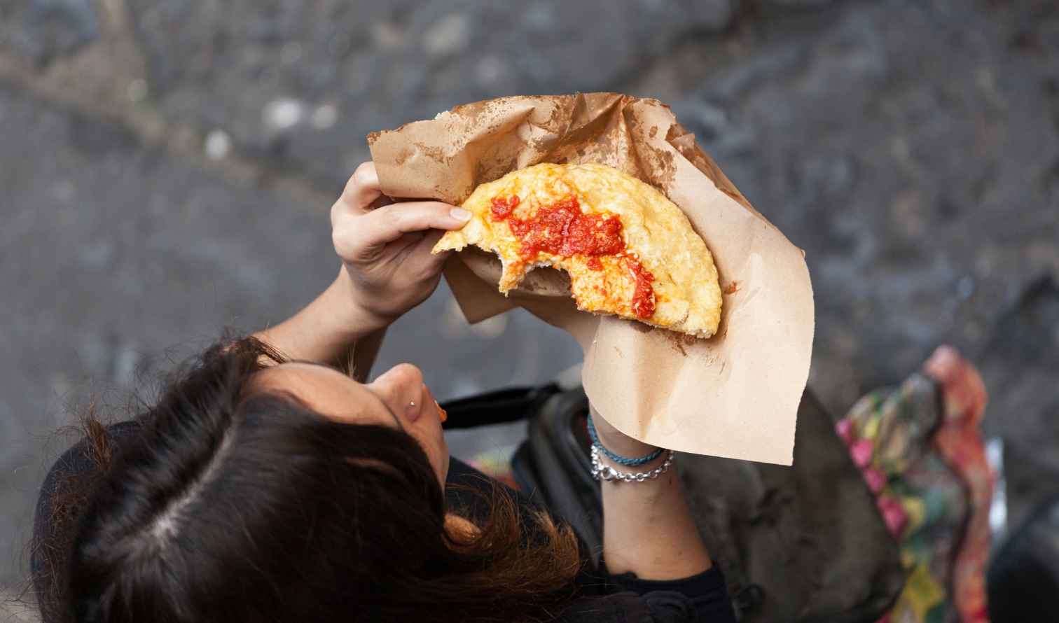 Person holding a fried pizza on Via dei Tribunali, Naples.