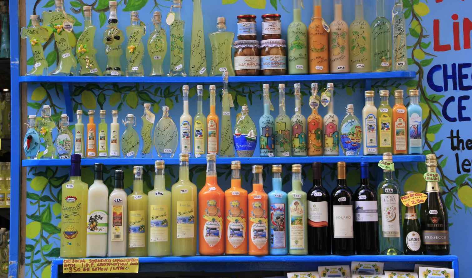 Colorful bottles of limoncello and wine on a decorated shelf in Naples