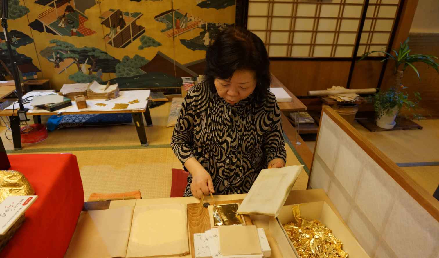 Artisan handling gold leaf sheets in a tatami room in Kanazawa