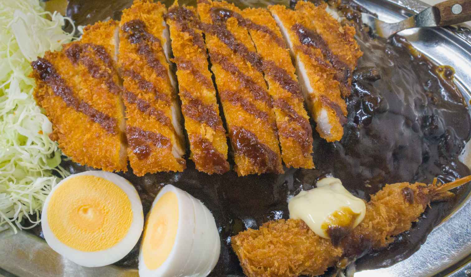 Pork katsu with curry sauce and boiled eggs on a silver platter in Kanazawa