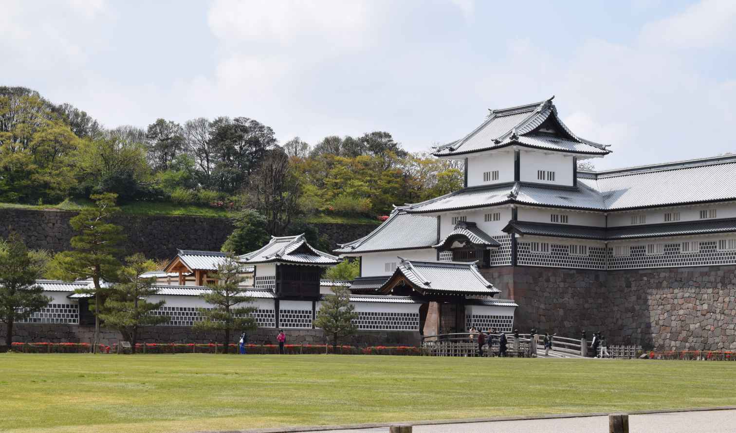 Traditional Japanese architecture of Kanazawa Castle under a partly cloudy sky.