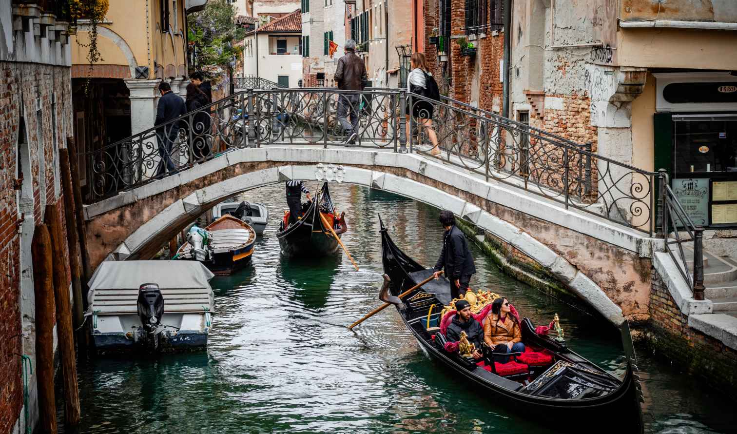 Gondola passing under a bridge in a narrow canal in Venice, Italy.