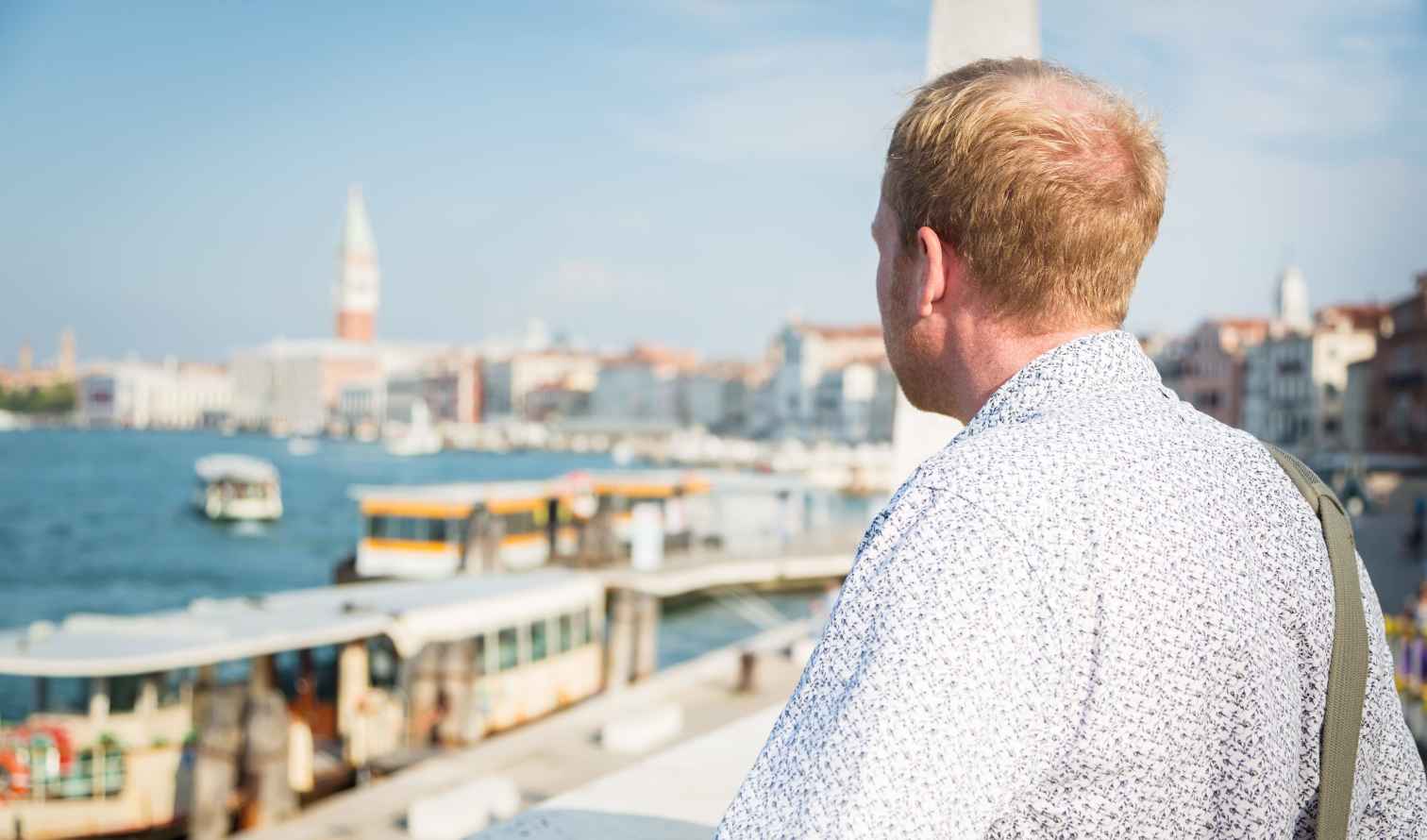 Individual viewing boats and buildings along the Grand Canal in Venice.