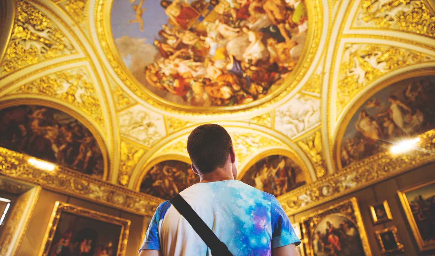 Man standing under detailed frescoes in the Vatican Museums  in Florence