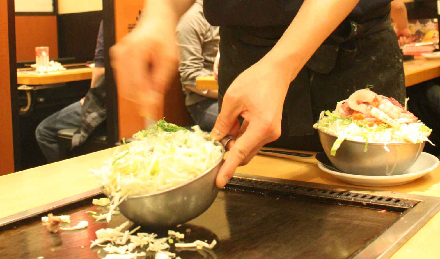 Person preparing food on a teppanyaki grill in a restaurant in Osaka