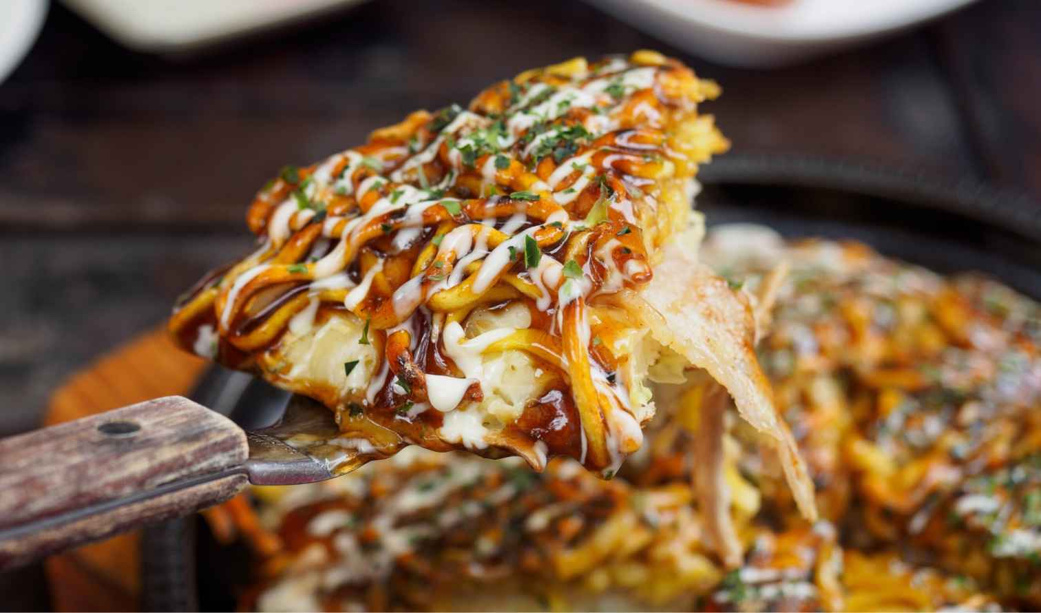 Close-up of okonomiyaki being served with a spatula in Osaka