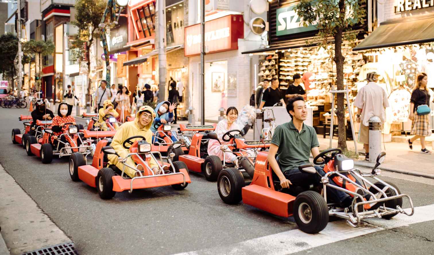 Street view of people in go-karts on a busy shopping street in Osaka