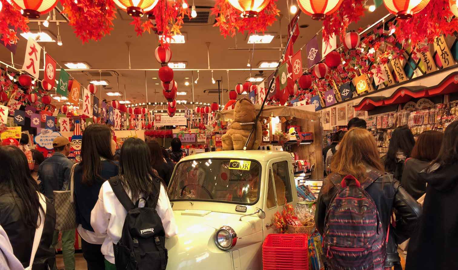 People inside a Japanese store with flags and lanterns overhead in Osaka.