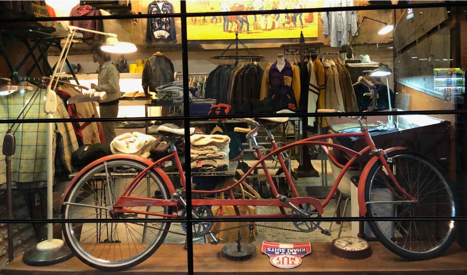 Shop window displaying vintage clothes and red tandem bicycle.