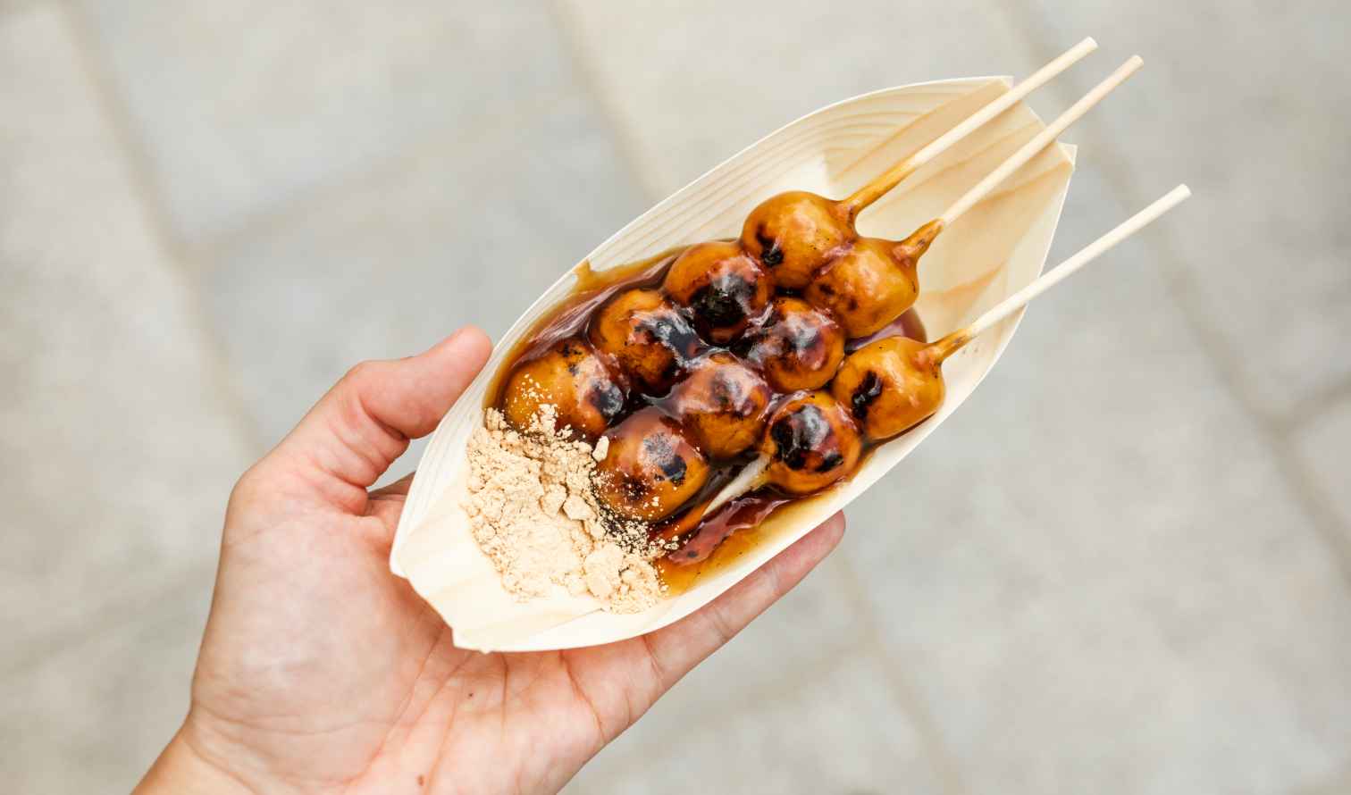 Close-up of hand holding skewered Japanese dango dessert in Osaka