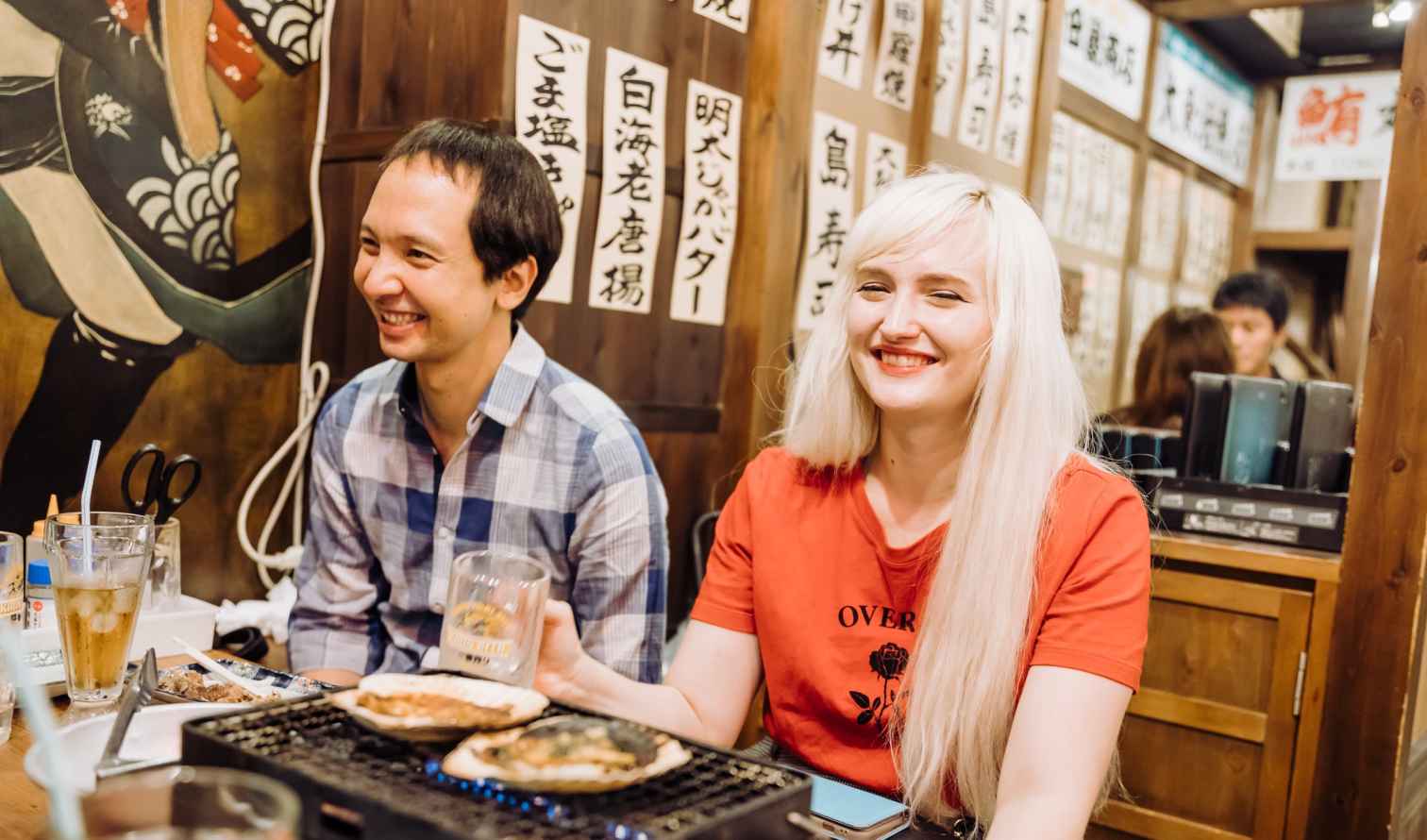 Two people sitting in a traditional Japanese izakaya restaurant in Osaka