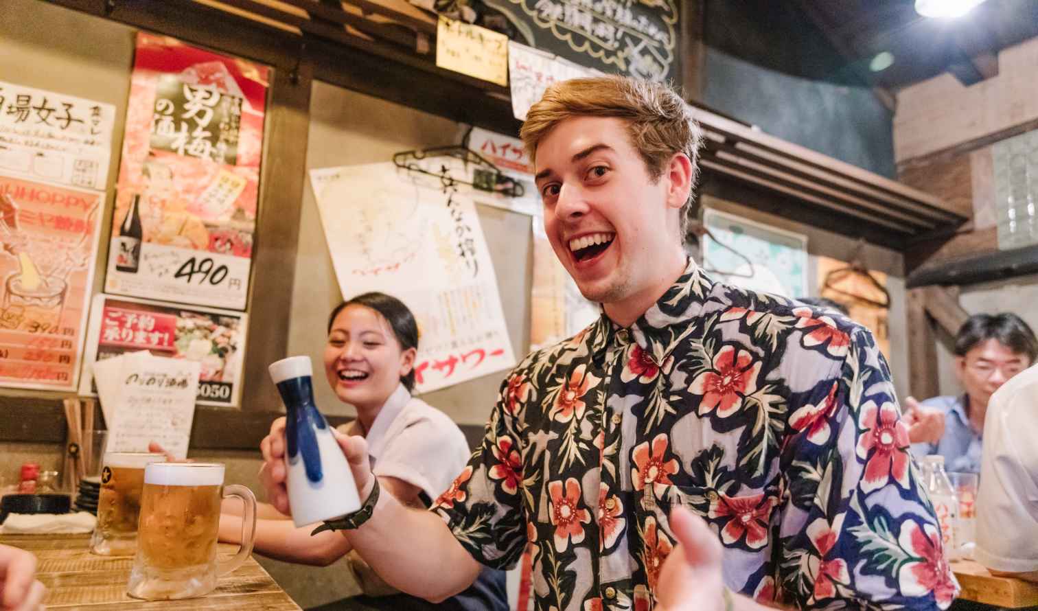 Interior view of a Japanese izakaya, people drinking and sitting at tables in Osaka