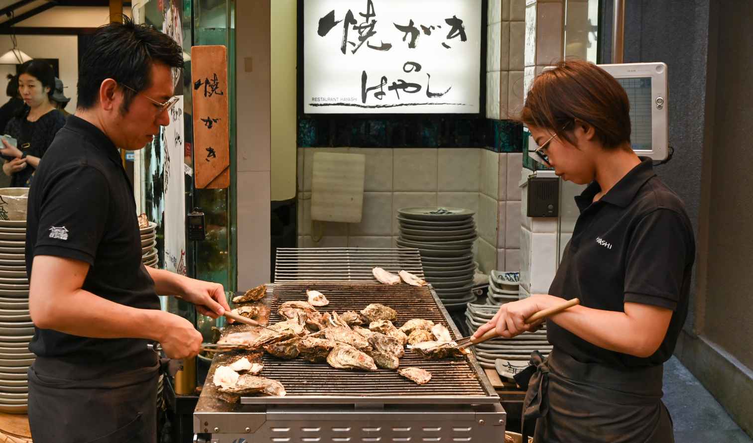 Two people grilling oysters at Restaurant Hayashi in Hiroshima