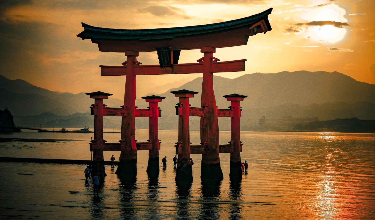 Itsukushima Shrine's floating torii gate in Hiroshima Bay at sunset.