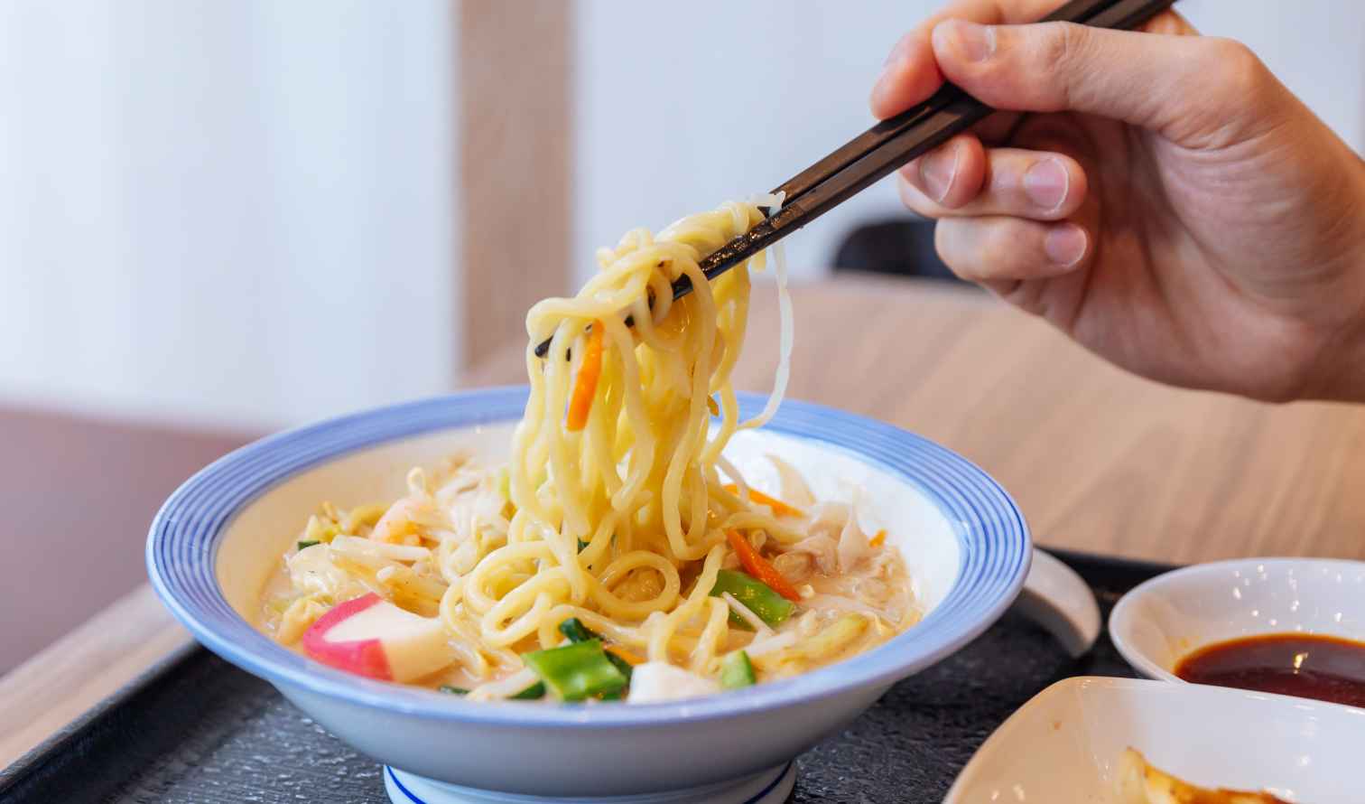 Hand using chopsticks to lift noodles from a bowl of ramen  in Nagasaki 