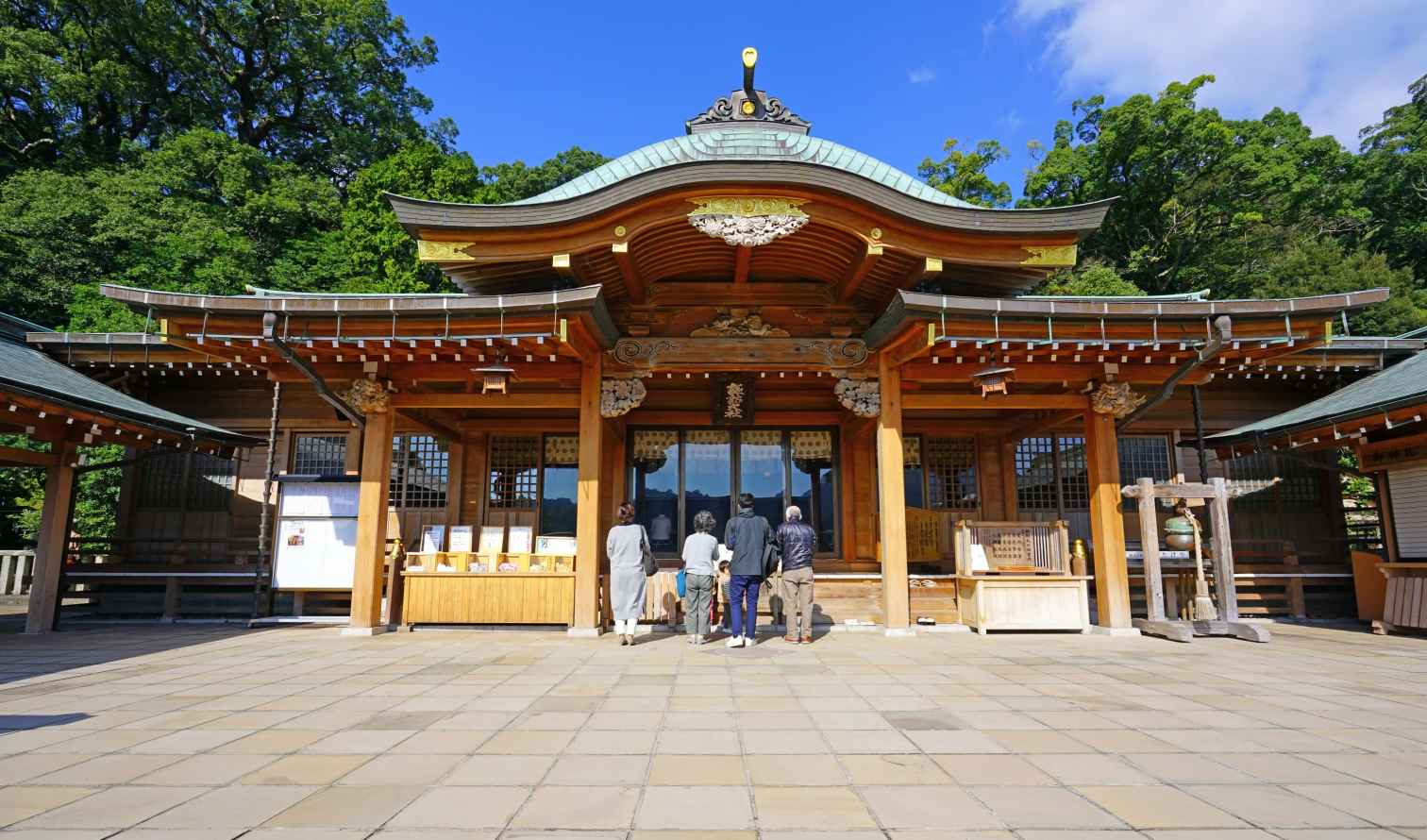 Visitors at the entrance of Chichibu Shrine are surrounded by lush greenery in Nagasaki