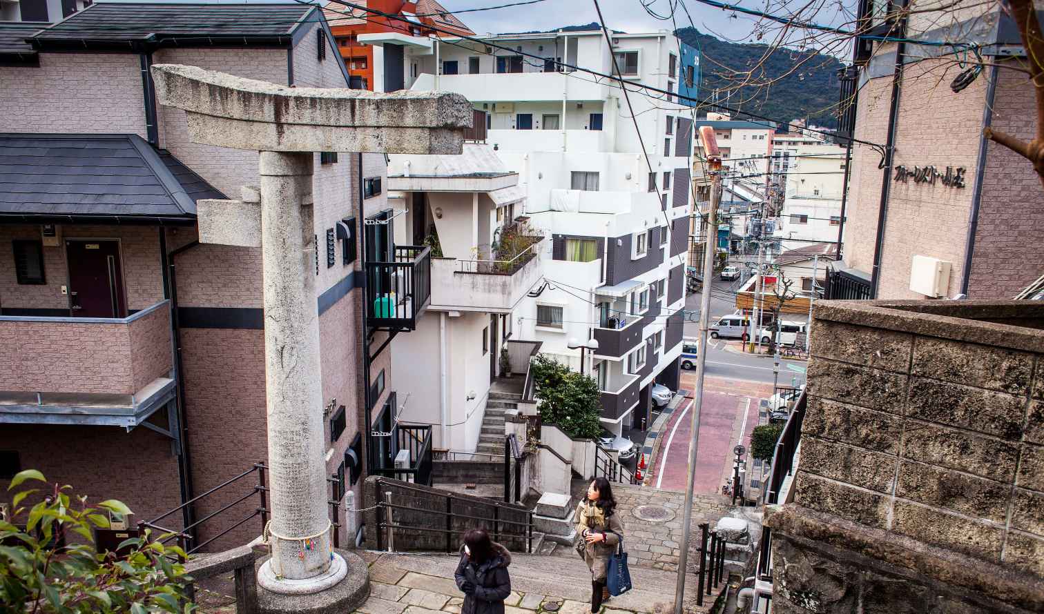 A torii gate stands on a narrow street in a Japanese neighborhood in Nagasaki.