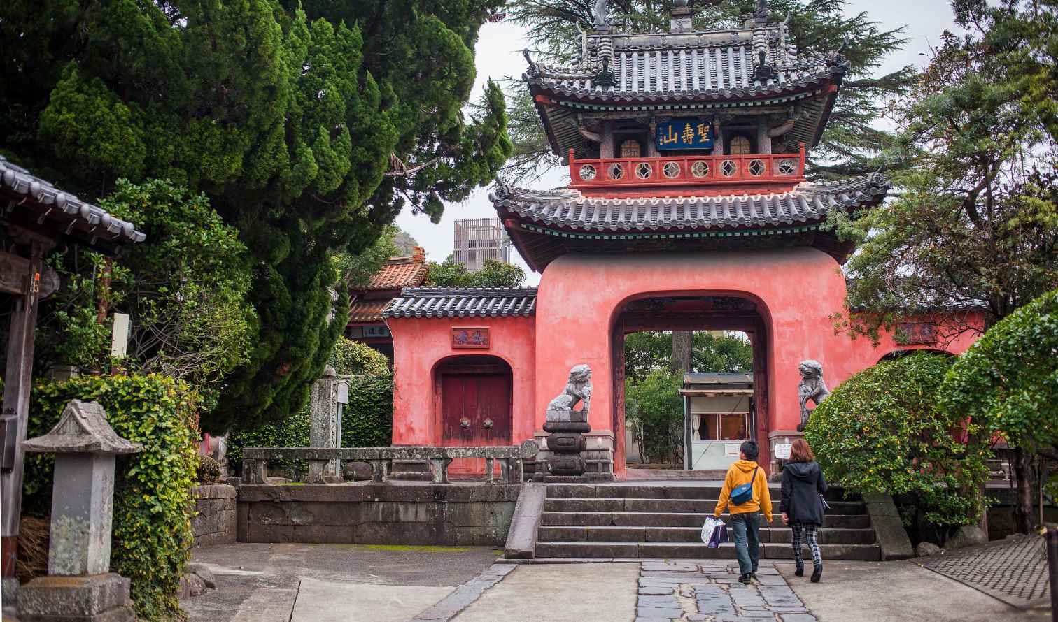 Two people walking towards the entrance of Sofukuji Temple in Nagasaki, Japan.