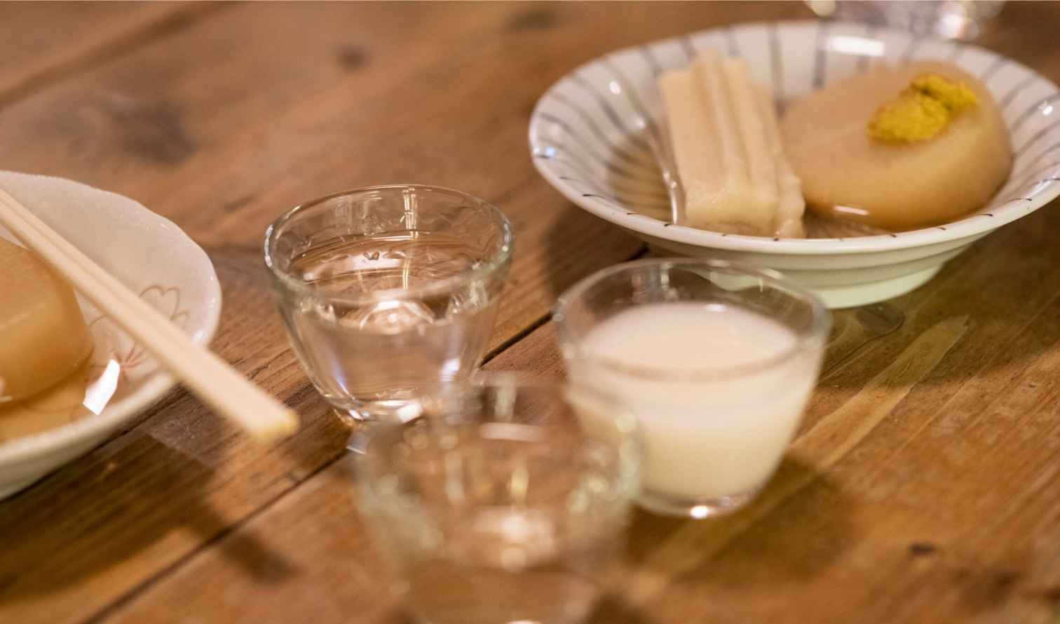Close-up of oden dishes with glass cups filled with drinks nearby in Kanazawa