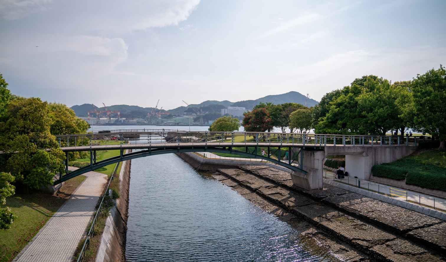 Green bridge over a canal with hills in the background in Nagasaki, Japan.