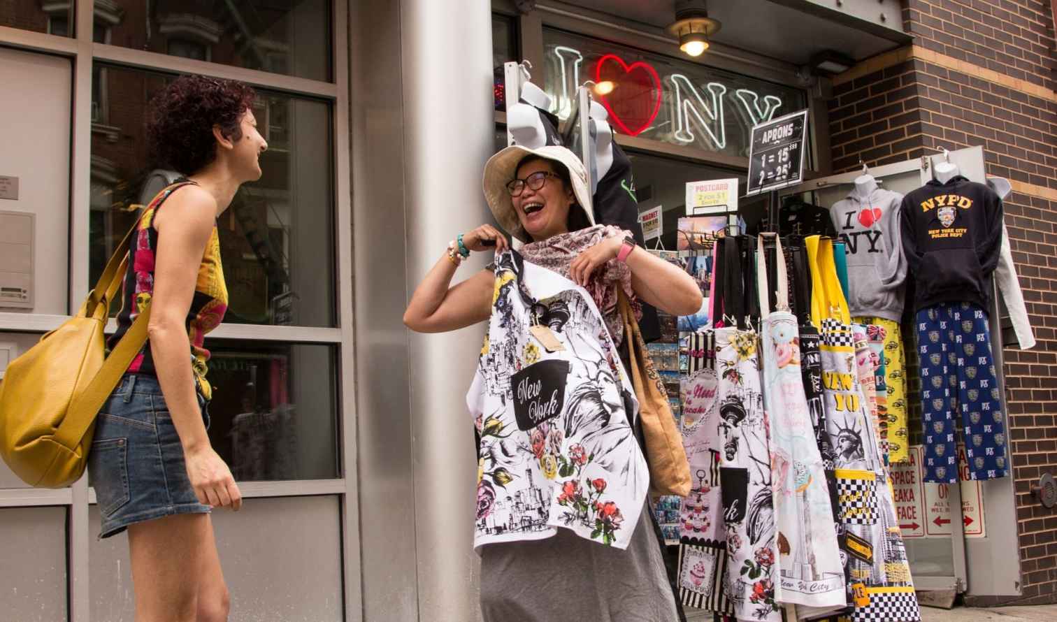 Two women at a souvenir shop in New York City showing a New York apron.