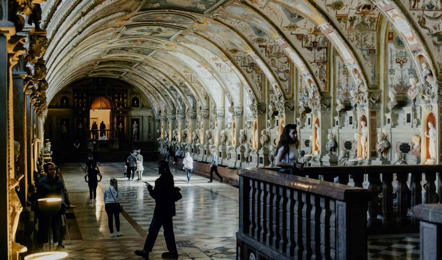 The gallery within the Munich Residenz shows ornate ceilings and sculpture-lined walls.
