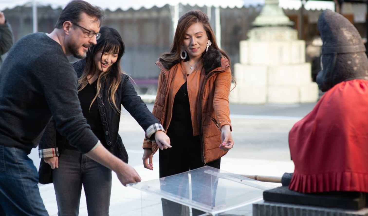 Visitors at a temple observing a statue with a red cloth in Tokyo.