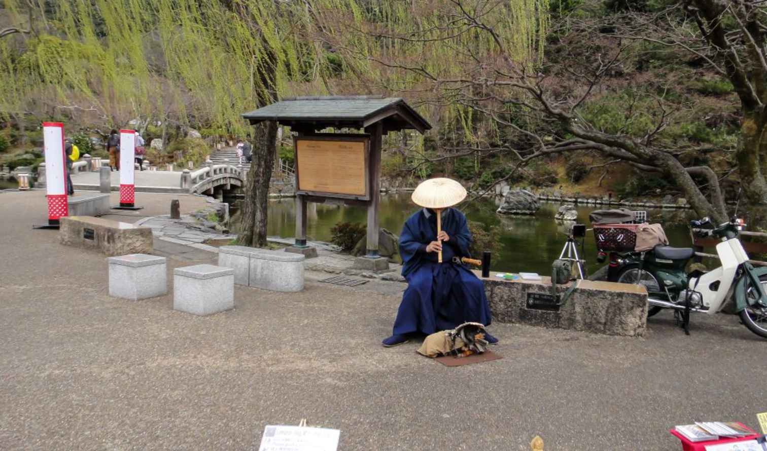 A person plays an instrument near the Togetsukyo Bridge in Arashiyama, Kyoto.