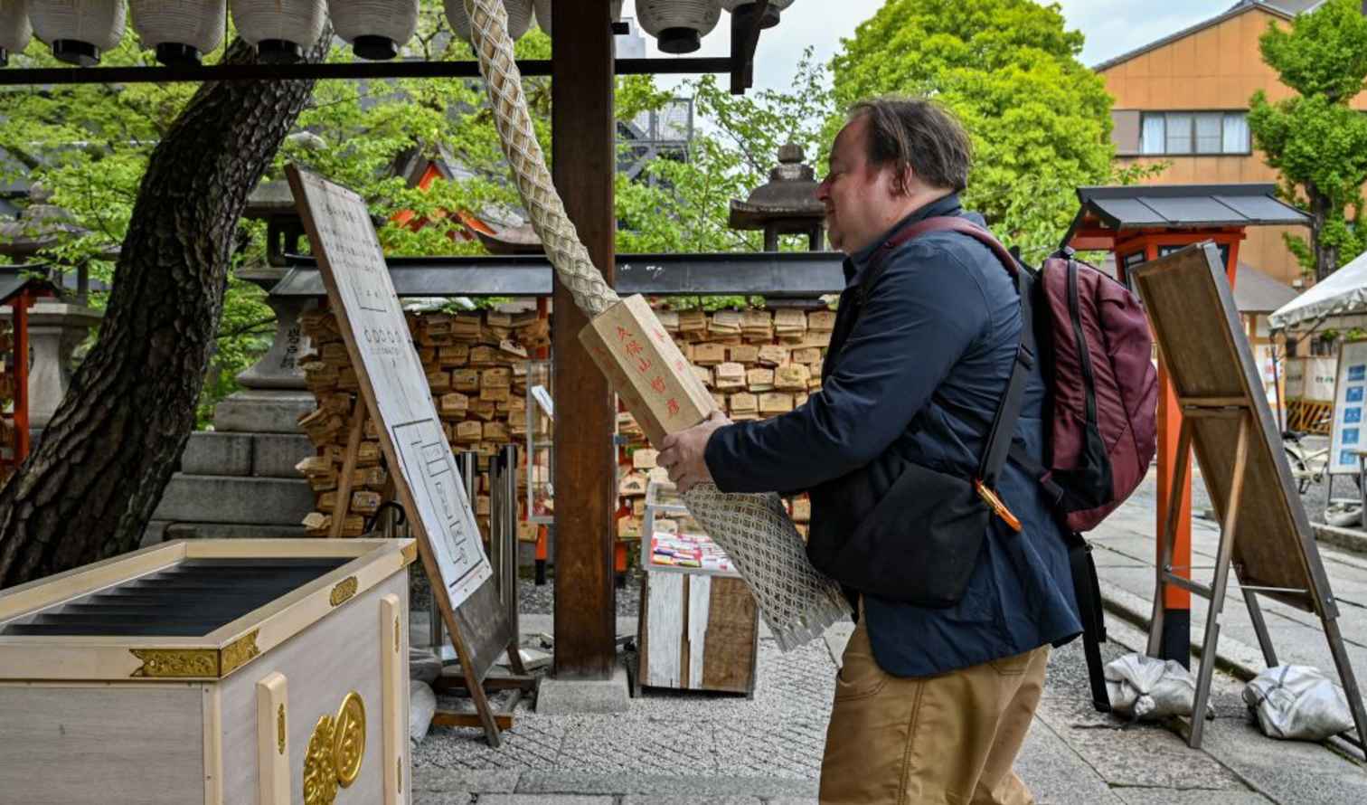 Man ringing a bell at a Japanese temple shrine in Kyoto