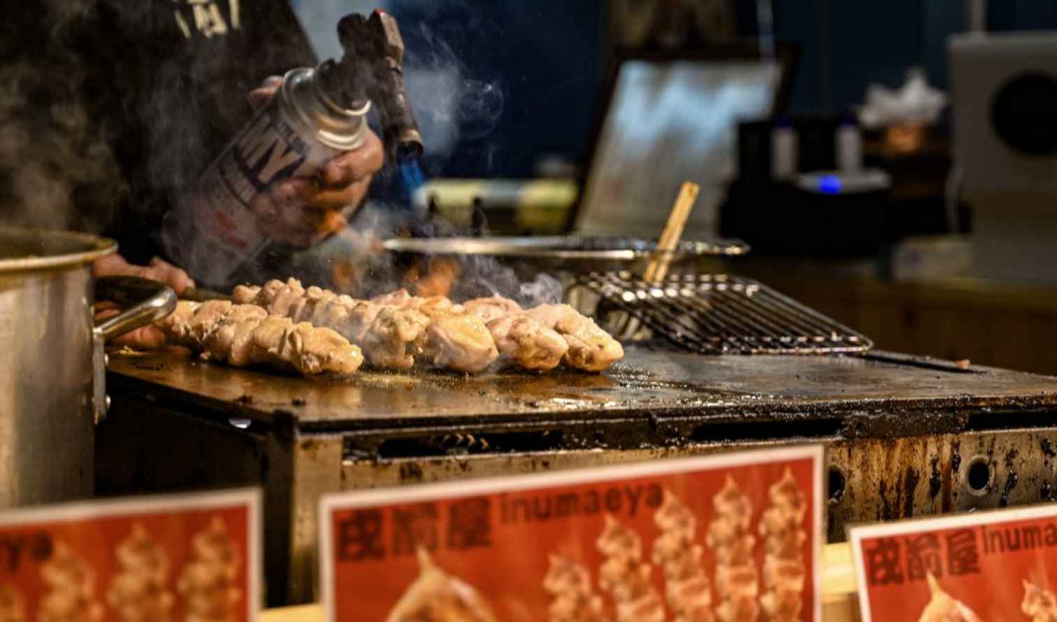 Food stall with skewers on grill and visible cooking equipment.