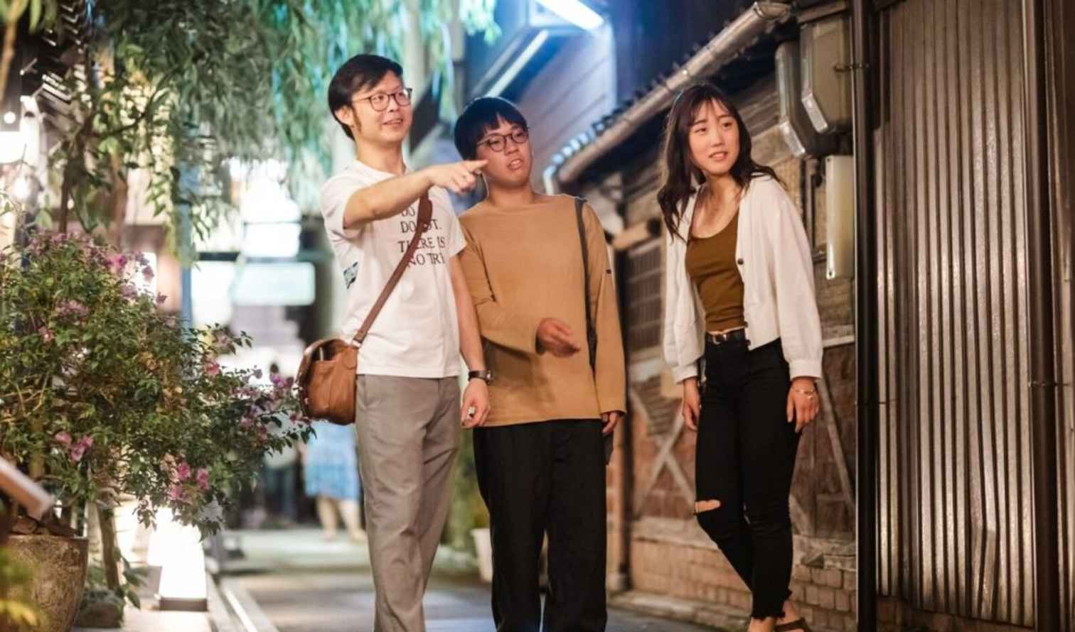 Three people walking on a narrow street in Kyoto