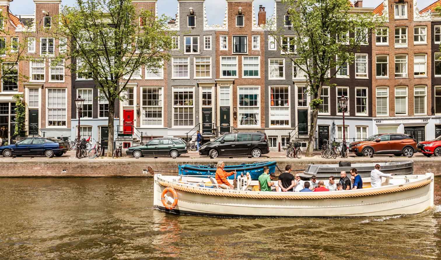 Canal boat passing by traditional houses in Amsterdam.