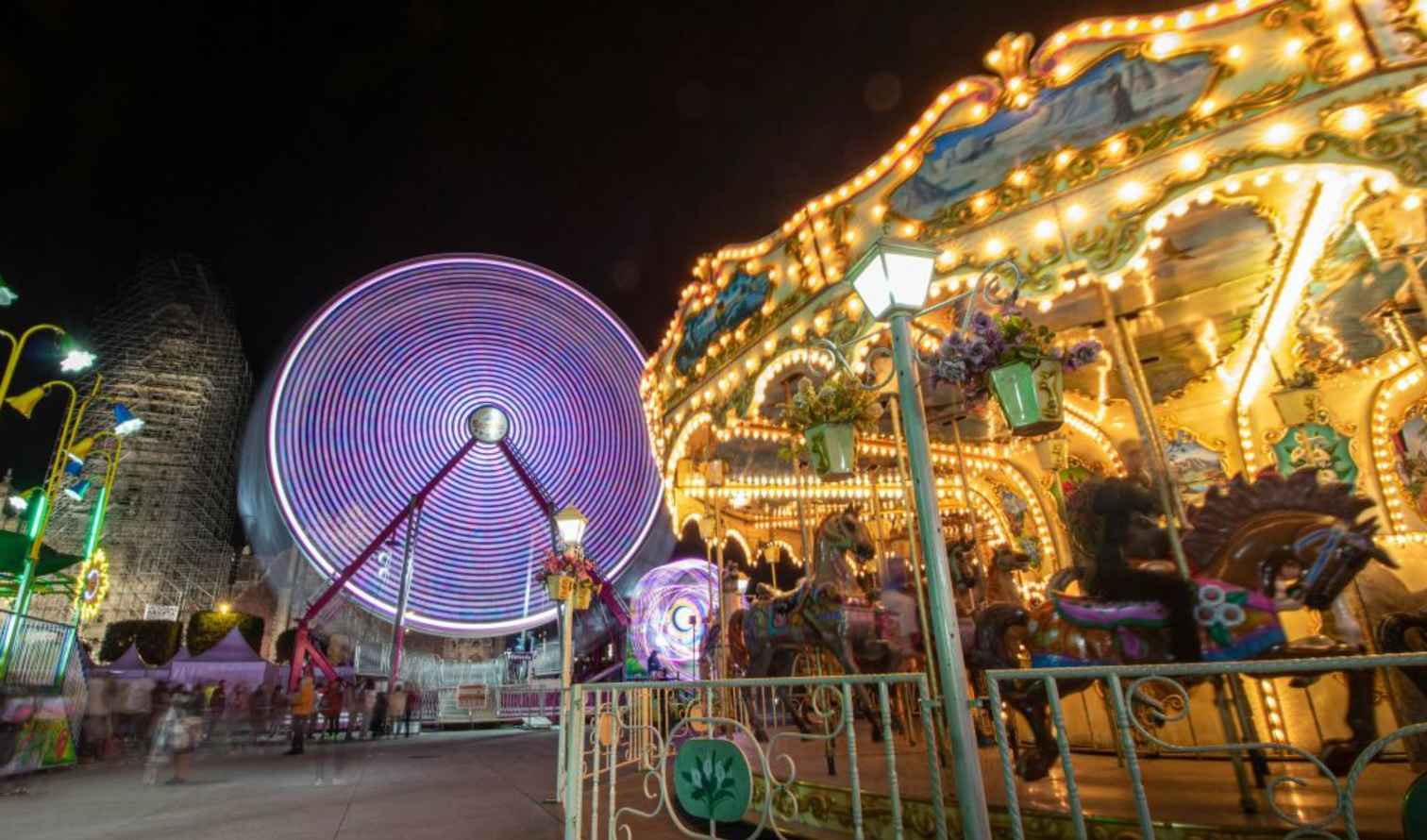 Nighttime view of a Ferris wheel and carousel at a carnival in Mexico