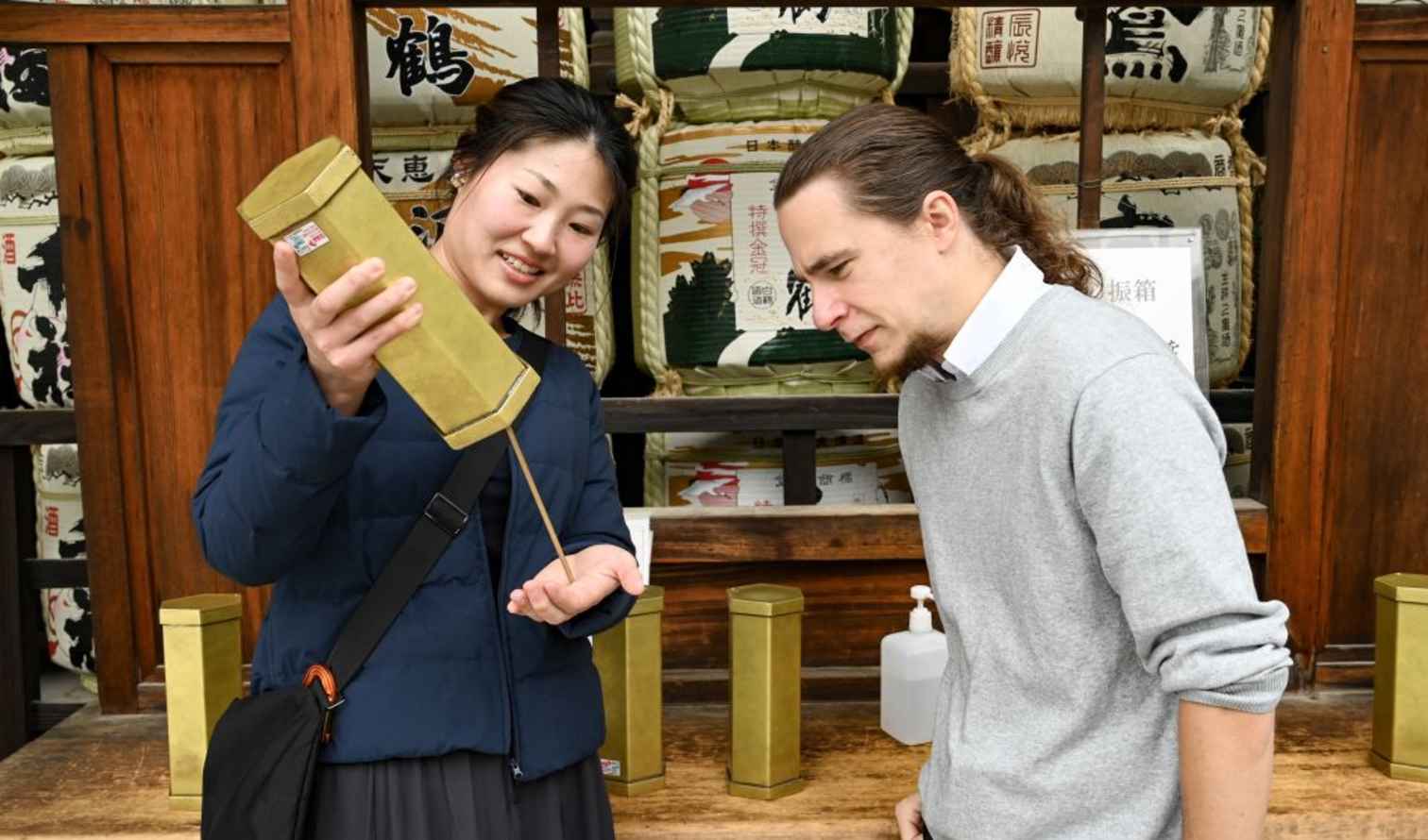 Sake barrel display with two people in traditional Japanese setting in Kyoto