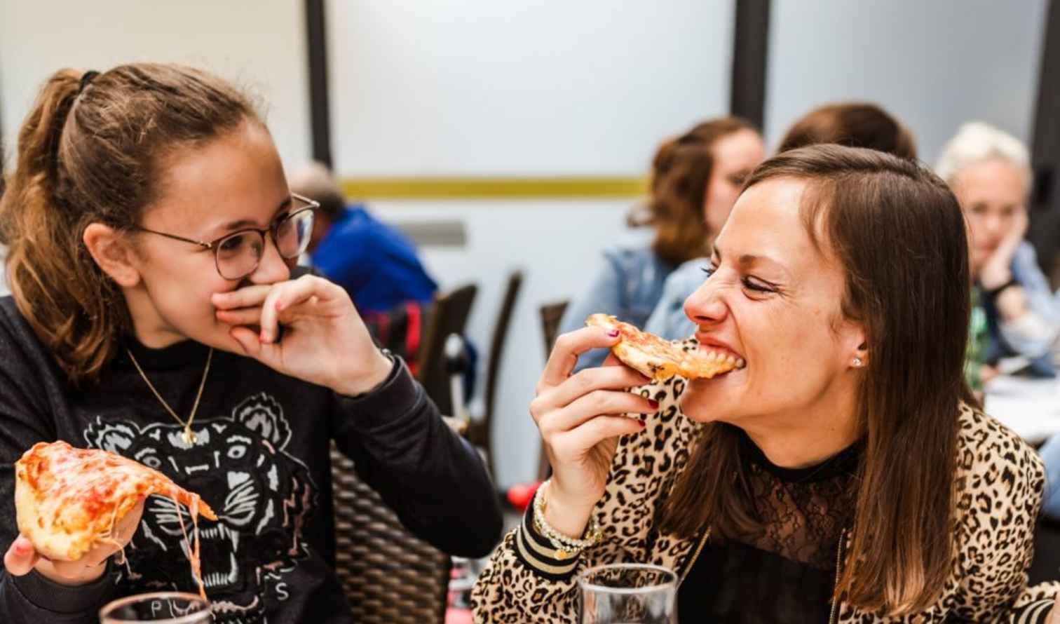 Two people eating pizza at an outdoor cafe in Milan